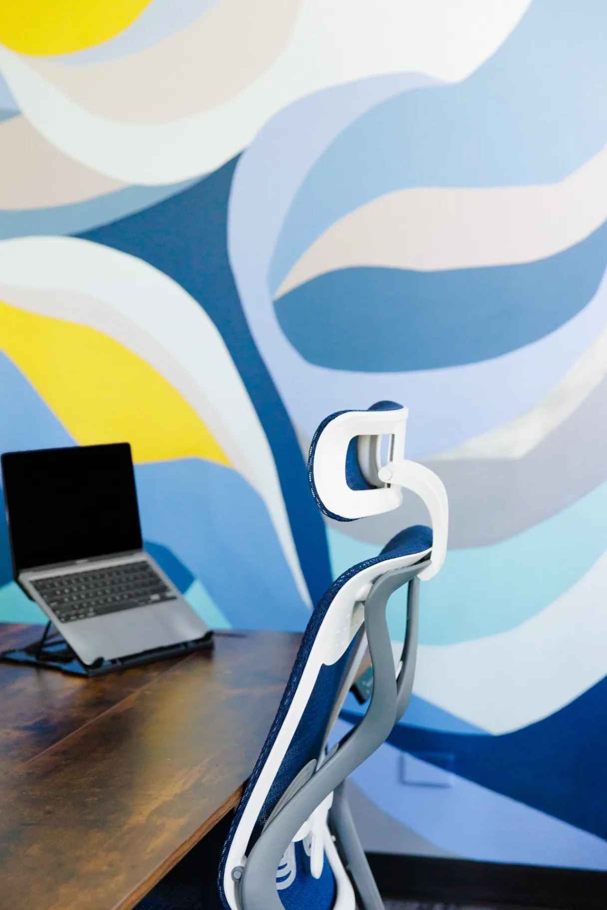 A King Work desk set against the signature blue and yellow mural